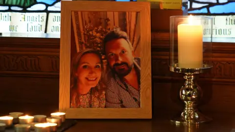 PA Media Candles are lit around a photo of Nicola Bulley (left) and her partner Paul Ansell on an altar at St Michael's Church