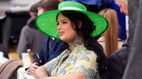 PA Media Woman in green hat watching racing at Aintree Ladies Day 2024