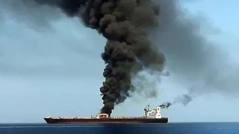 AFP/HO/IRIB Image from Iranian State TV showing smoke billowing from a tanker in the Gulf of Oman