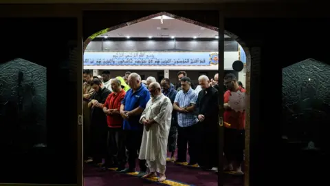 Getty Images Mourners praying at a mosque in Sydney the morning after the Christchurch shootings