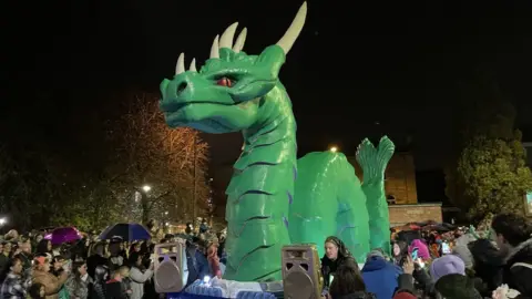 A large green dragon float in the Derry Halloween parade