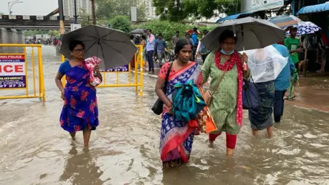 People wade through a flooded street