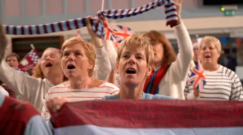 A group of women waving Aston Villa flags and singing