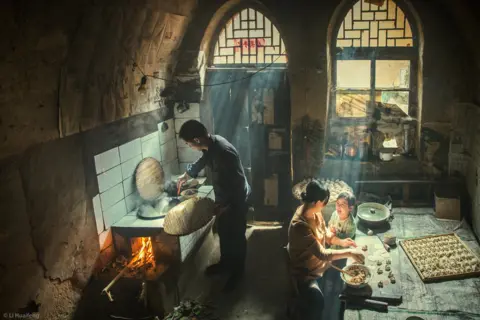 Li Huaifeng Family preparing food indoors, with rays of sunlight shining through the windows