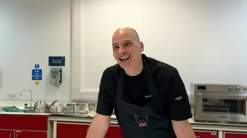 Patrick Clifford stands in his kitchen smiling