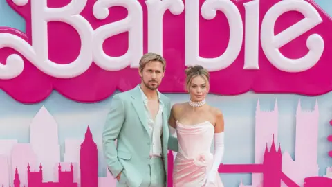 Ryan Gosling and Margot Robbie, the stars of Barbie, at one of the film's premieres in 2023. He is wearing a mint green suit an she is wearing a light pinj strapless dress.