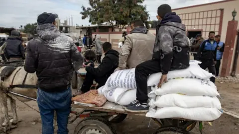 Palestinos da EPA recebem sacos de farinha distribuídos pela UNRWA em Rafah, sul da Faixa de Gaza, em 28 de janeiro de 2024
