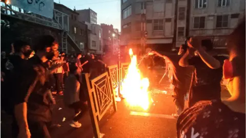 Getty Images Protesters setting gate on fire in Tehran