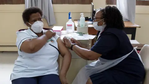 AFP A nurse gets a temperature check before receiving a dose of the Johnson & Johnson vaccine against the COVID-19 coronavirus as South Africa proceeds with its inoculation campaign