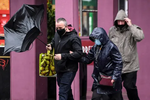 AFP Pedestrians wearing protective face masks struggle against the wind in Glasgow city centre on August 25, 2020, as Storm Francis brings rain and high winds to the UK.