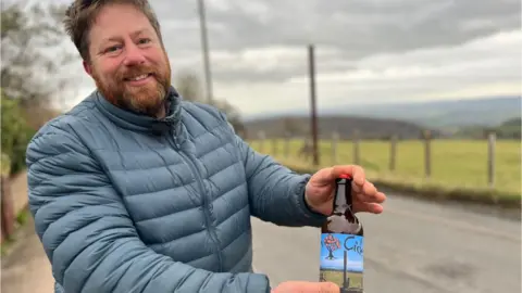 Tom Bull holding a bottle of the rusty pole cider