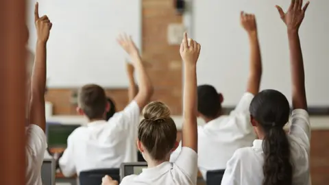 Getty Images children in classroom raising their hands