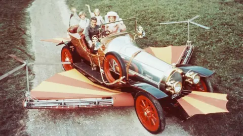 Silver Screen Collection/Getty Photo issued for the 1968 film Chitty Chitty Bang Bang showing Dick Van Dyke, Heather Ripley, Adrian Hall and Sally Ann Howes sit waving from their seats in the car
