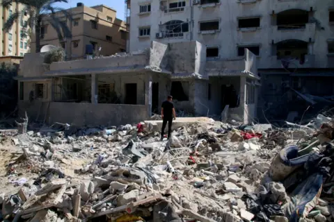 Getty Images Palestinian citizens inspect damage to their homes in Khan Younis