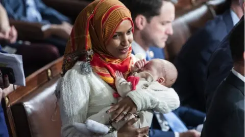 EPA Democratic Representative Ilhan Omar holds the child of Democratic Representative Eric Swalwell while waiting for Democratic House Leader Nancy Pelosi to accept the gavel to once again become Speaker of the House in the US Capitol in Washington