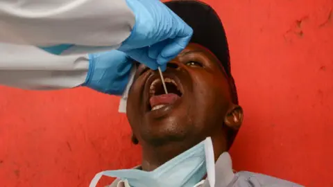 Getty Images A health worker performs a mouth swab test on a resident during the corona virus pandemic.