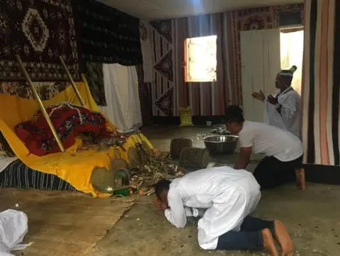 Adedayo Okedare/BBC Worshippers offering prayers at the priestess's shrine early morning ahead of the procession to the Osun Osogbo Grove