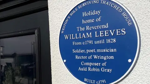Old Thatched Cottage restaurant The blue plaque, which reads 'Holiday home of the Reverend William Leeves, from c.1791 until 1928. Solider, poet, musician, Rector of Wrington, composer of Auld Robin Gray'