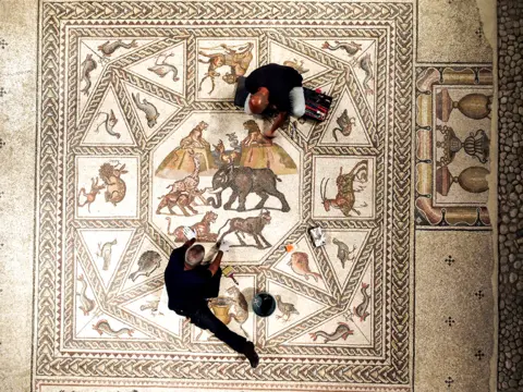 Amir Cohen / Reuters Workers clean a restored Roman-era mosaic after it was put on display at its original site in Lod, Israel, on 27 June 2022