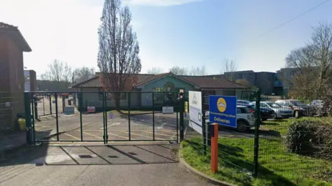 Google The outside of a primary school. It is a sunny day. The sky is clear. 