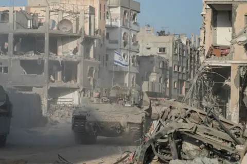 Israeli troops and an armored personnel carrier patrol the streets of rubble-strewn Rafah in September 2024