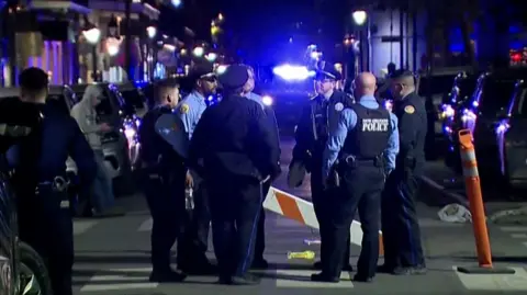 Police stand in dark at attack scene in new orleans.