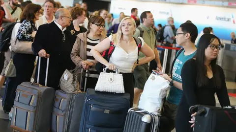 Getty Images People queue at an airport