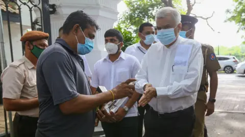 EPA Leader of the United National Party (UNP) Ranil Wickremesinghe, sanitise his hands before entering a polling station during the parliamentary election, in Colombo, Sri Lanka, 05 August 2020.