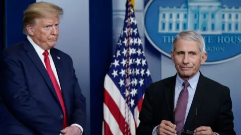 Getty Images President Donald Trump looks at Dr Anthony Fauci as he walks off the podium, 22 April 2020