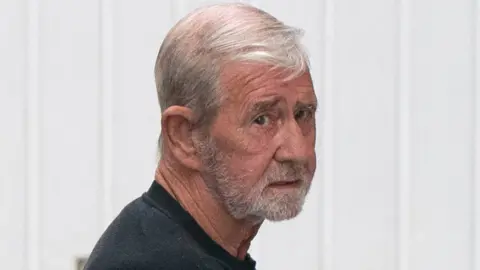 PA Media David Hunter wearing a black top and white beard arrives at court