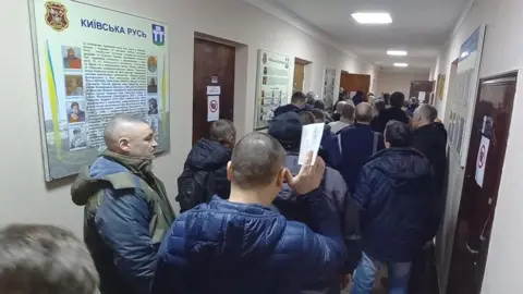 Reuters Volunteers wait in line to join the Ukrainian Armed Forces at a military commissariat in Rivne, Ukraine