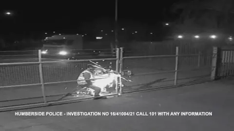 Two men using an angle grinder to cut through a locked gate