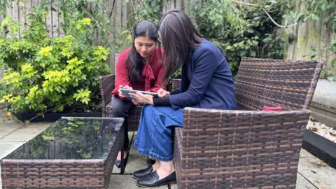 Sara (r) with cousin Dr Sancy Low looking at pictures of Mr Teoh