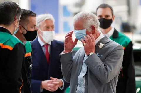 Peter Nicholls / AFP Britain's Prince Charles puts on a face covering