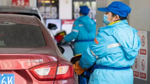 Getty Images Petrol station worker in China fills car with fuel.