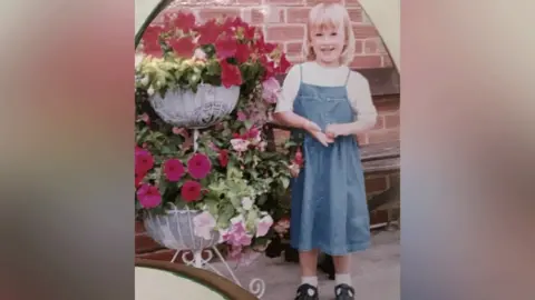 Hales family Emily Hales as a child standing next to baskets of flowers on a patio