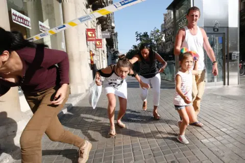 PAU BARRENA/ Getty Images People duck under a cordon