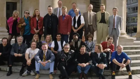 Radio 1 DJs outside All Souls Church, London, in 1992. (Back row l-r): Annie Nightingale, Alan Freeman, Dianne Oxberry, Pete Tong, Bob Harris, Nicky Campbell, Johnnie Walker, Alan Robb, Paul Gambaccini, Simon Mayo and unknown. (Front l-r): Steve Wright, Dave Lee Travis, Jakki Brambles, Adrian Juste, Lynn Parsons, Rod McKenzie, Gary Davis, Tommy Vance, Man Ezeke, Nicky Horne, Sybil Ruscoe, Bruno Brookes, Mark Goodier and John Peel.