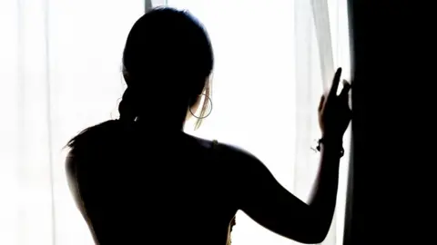 Getty Images Woman looking out of window, stock image