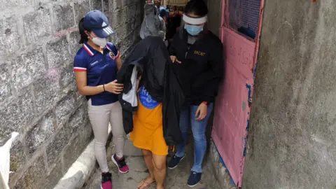 Philippines National Police A mother involved in abuse is lead away by the police