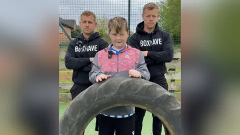 Supplied Harry and Joe Freeman stood in branded Boxwave hoodies, arms crossed, either side of Liam.