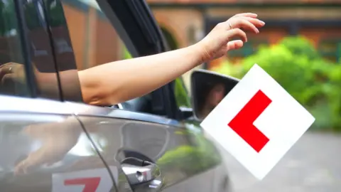 Getty Images A driver throwing their learner plate away