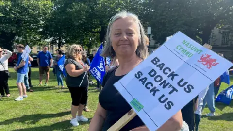 BBC Sport Person at strike with a sign saying "Back us don't sack us"