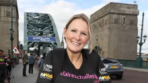 A woman in a black top crossing a bridge