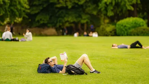 PA Media People relax in the sun on the grass at the Royal Crescent, Bath. Picture date: Monday June 13, 2022.