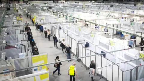 PA Media Health and social care staff queue for a coronavirus vaccine at the NHS Louisa Jordan Hospital in Glasgow
