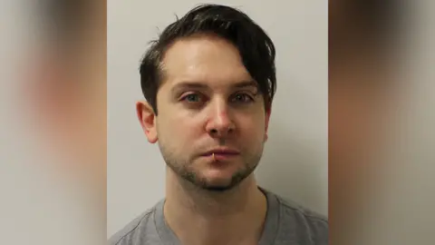 Custody image of Ross Davidson. He has short brown hair and a lip ring