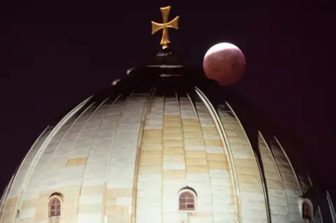 EPA A view of the lunar eclipse above the St Elizabeth Church in Nuremberg, Germany