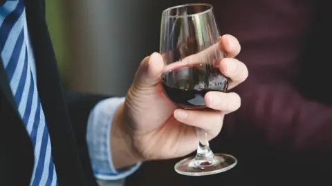 Getty Images Hand holding glass of red wine