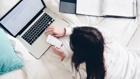 Getty Images Girl on bed looking at a computer